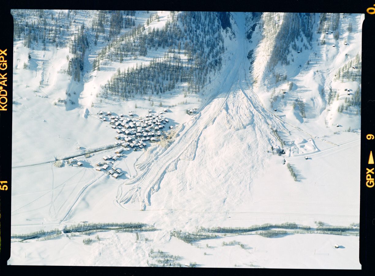 Im Trützital hat am 22. Februar 1999 eine sehr grosse Staublawine den Lawinendamm auf der Westseite von Geschinen weitgehend hinterfüllt und so unwirksam gemacht. Bis am Folgetag sind noch vier weitere Lawinen bis in den Talboden vorgestossen. Die letzte dieser Lawinen hat ein Haus zerstört. Ein Mann, welche die Evakuation verweigert hatte, konnte nur noch tot geborgen werden. Aufnahmerichtung: SE, 26. 02. 1999, 16:05; Titel der Aufnahme: GESCHINEN; Goms, Wallis Kameramodell: Expression 11000XL